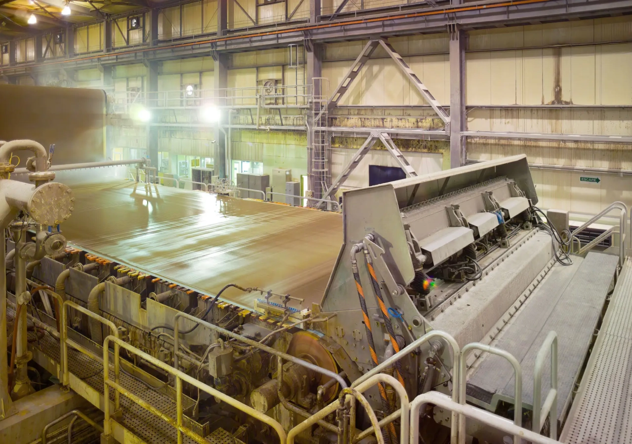 Interior of a large industrial steel manufacturing plant with heavy machinery.