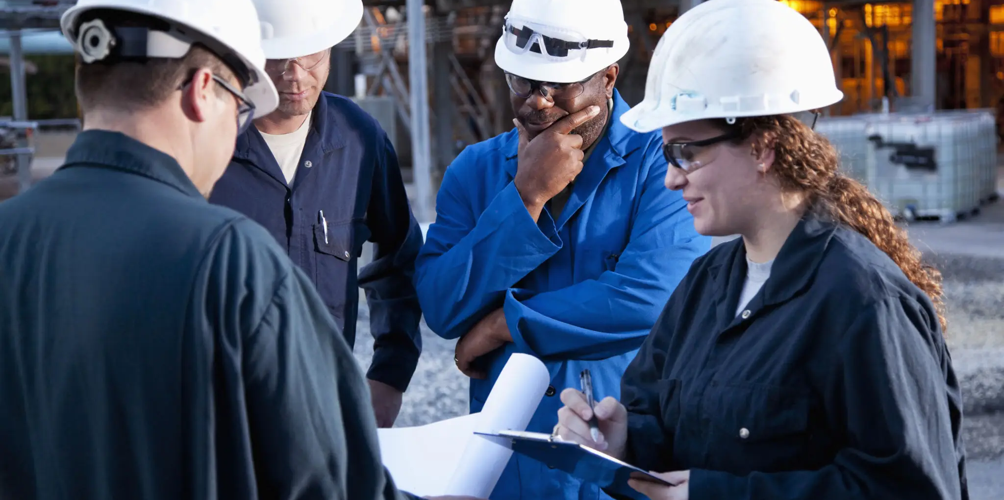 Engineers in hard hats discussing project plans at a construction site.